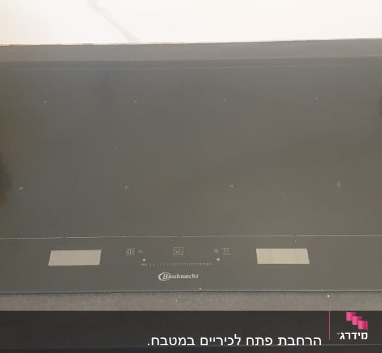 כיריים חשמליות על משטח שיש כהה במטבח